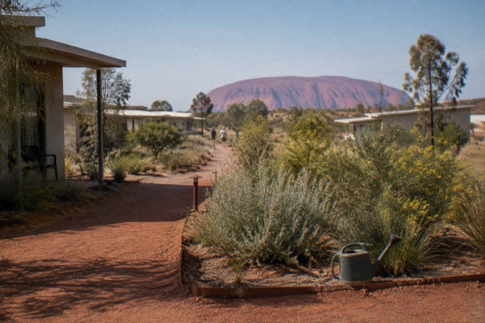 Low-rise resort buildings set among native desert gardens and red dirt paths