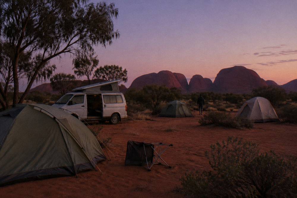 Campground with tents and a campervan under a wide evening sky